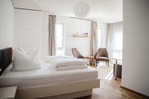 a white bedroom with a bed and a desk at Maiers Johanniterbad Ringhotel Rottweil in Rottweil