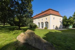 uma grande rocha na relva em frente a um edifício em Orangerie im Schlosspark zu Arnsdorf em Arnsdorf