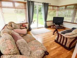 sala de estar con sofá y TV de pantalla plana en Moybella Lodge, en Ballybunion