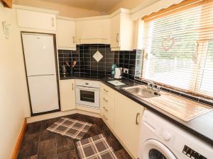 een keuken met witte kasten, een wastafel en een raam bij Moybella Lodge in Ballybunion