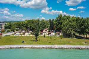 a park with people sitting on the grass near the water at Happy Camp mobile homes in BalatonTourist Füred Camping & Bungalows in Balatonfüred