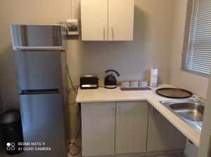 a small kitchen with a refrigerator and a sink at Atholl Heights Home - BnB 1 in Westville