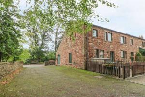 un edificio de ladrillo con una valla delante en 1 Friary Cottages, Appleby-in-Westmorland en Appleby