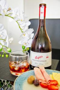 una botella de vino sentada junto a un plato de comida en Absolute Waterfront - Tropical Aurora Top Floor Over The Water, en Darwin