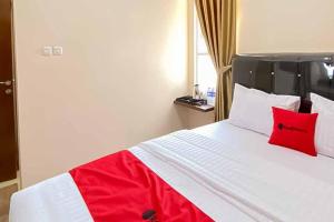 1 dormitorio con 1 cama blanca grande con almohadas rojas en RedDoorz Plus at Permata Gueshouse Lampung, en Lampung