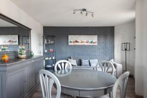 ein Esszimmer mit Tisch und Stühlen und einer Couch in der Unterkunft Appartement près du port centre et plage - Vue mer in Courseulles-sur-Mer