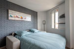a bedroom with a large bed and a brick wall at Appartement près du port centre et plage - Vue mer in Courseulles-sur-Mer
