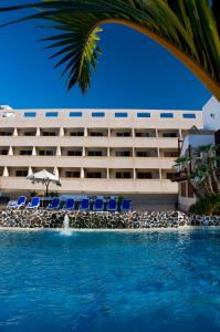 a hotel with a swimming pool in front of a building at Apartamentos Pirámides in Playa de las Americas