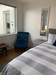 ein Schlafzimmer mit einem Bett und einem blauen Stuhl in der Unterkunft Zepher Apartment in Doolin