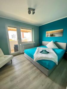 a blue bedroom with a bed and a chair at COAST HOUSE Dünenloft in Bremerhaven