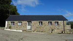 a stone house with a black roof on a street at Wild Coastal Retreat at Troed Y Rhiw Aberporth in Aberporth