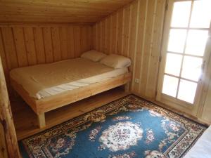 a small bed in a room with a rug and two windows at Le chalet de Cavailla in Marmont-Pachas