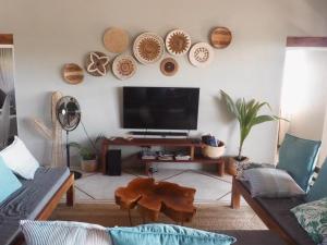 a living room with a flat screen tv on the wall at Casa Naroo in Praia do Tofo