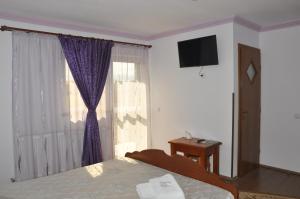 a bedroom with a bed and a window with a television at Vilman House in Râşnov