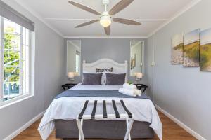 a bedroom with a bed with a ceiling fan at Lagoon View Cottage in Knysna