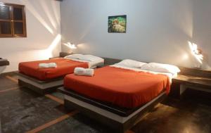 two beds in a room with red sheets at Posada Casa Las Trinitarias in Paraguachi