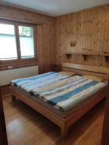 a bed in a room with wooden walls and windows at Chalet Pinocchio in Mühlebach