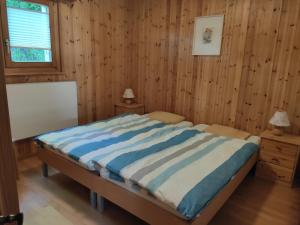 1 dormitorio con 1 cama en una pared de madera en Chalet Pinocchio, en Mühlebach