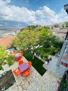 a patio with chairs and tables and a tree at Mani Guest House in Gjirokastër