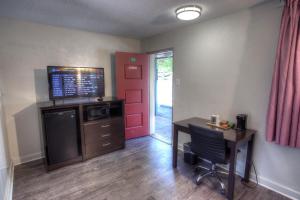 a room with a desk and a tv and a door at Hofbrau Riverfront Hotel in Helen