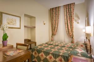 a hotel room with a bed, table, lamp and window at Hotel Aberdeen in Rome