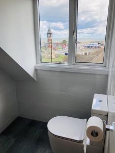 a bathroom with a toilet and a window with a clock tower at Marine Boathouse View Apartment in Skegness