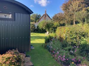 un giardino con un capanno nero e alcuni fiori di Corner House a Cudworth