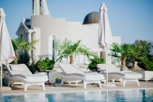 un grupo de sillas y sombrillas blancas junto a una piscina en Hotel Lion en Ulcinj