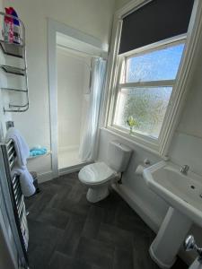 a bathroom with a toilet and a sink and a window at Shiray Hotel in Blackpool