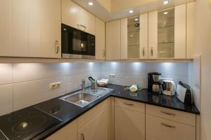 a kitchen with white cabinets and a sink at Haus am Park Wohnung Nr3 in Spiekeroog
