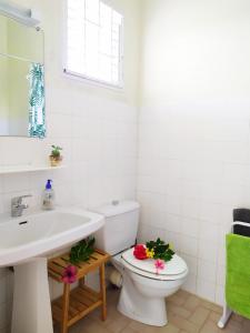 ein Badezimmer mit einem Waschbecken und einem WC mit Blumen darauf in der Unterkunft Studio Goyave in Ducos