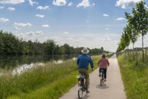 a man and a child riding bikes down a path next to a river at Aux Nobles Acacias in Épagne-Épagnette