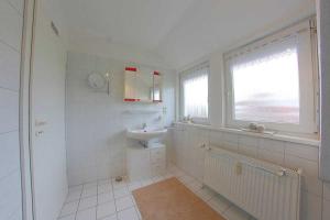 een witte badkamer met een wastafel en een raam bij MU32a Dachgeschoss in Dorum Neufeld