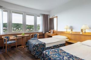 Cette chambre d'hôtel comprend deux lits, une table et des chaises. dans l'établissement Hotel Budapest, à Budapest