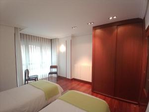a hotel room with two beds and a wooden cabinet at Apartamento Ana con garaje in Éibar