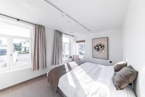 a bedroom with a bed and two windows at Hoeve De Blauwe Zaal in Bruges