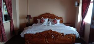 a bedroom with a wooden bed with white sheets and pillows at RISE N SHINE HOMESTAY in Darjeeling