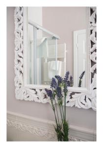 a mirror on a wall with purple flowers in a vase at Casa Antonelli in San Benedetto del Tronto