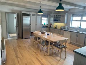 a large kitchen with a table and a refrigerator at The Cuan House in Strangford
