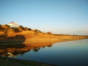 a house sitting on top of a hill next to a river at Herdade Monte da Tapada in Alqueva