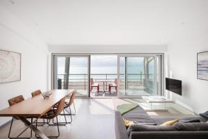 Lancing beach apartment. في لانسينغ: غرفة معيشة مع طاولة وكراسي وإطلالة على المحيط