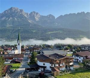 una piccola città con una chiesa e montagne sullo sfondo di KAISERapart ELLMAU Zentrum a Ellmau