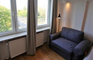 a living room with a blue chair and a window at Apartament MGM Karmelicka in Warsaw