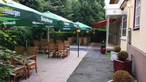 a patio with tables and chairs and a green umbrella at Hotel-Restaurant Babylon in Dierdorf