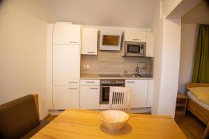 a small kitchen with white cabinets and a wooden table at Gasthof-Pension Riedl in Vöcklamarkt