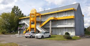two cars parked in a parking lot in front of a building at Premiere Classe Agen in Agen
