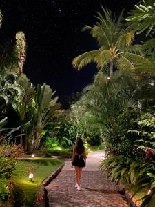 a woman walking down a path in a garden at night at Jardin del Eden Boutique Hotel in Tamarindo