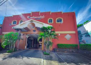 a red building with palm trees in front of it at Hotel Continental Plaza in San Miguel