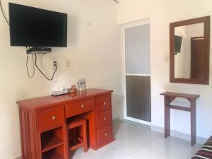 a room with a wooden dresser and a television on a wall at Hotel Maya Balam in Xpujil