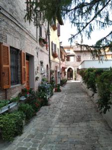 Une allée dans un vieux bâtiment avec des fleurs et des plantes dans l'établissement Il Borghetto Medievale suite, à Fabriano
